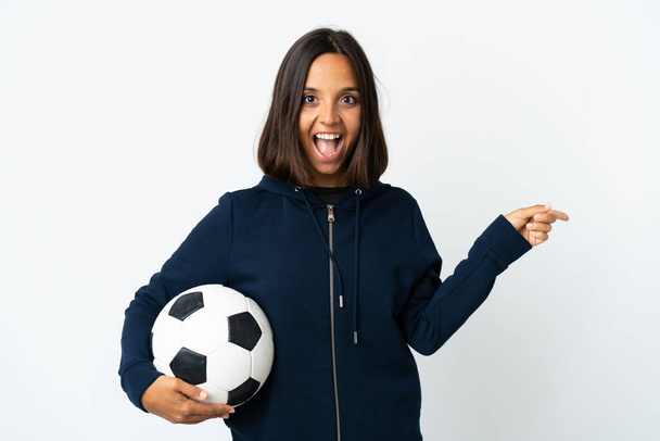 Mladý fotbalista žena izolované na bílém pozadí překvapen a ukazující prstem na stranu - Fotografie, Obrázek