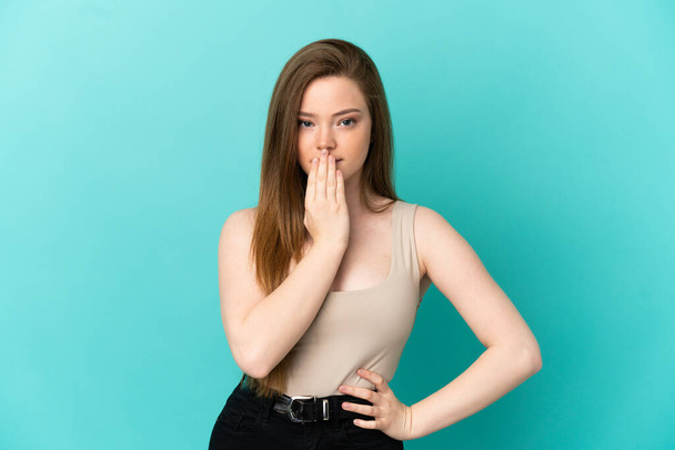 Teenager dívka přes izolované modré pozadí pokrývající ústa s rukou - Fotografie, Obrázek