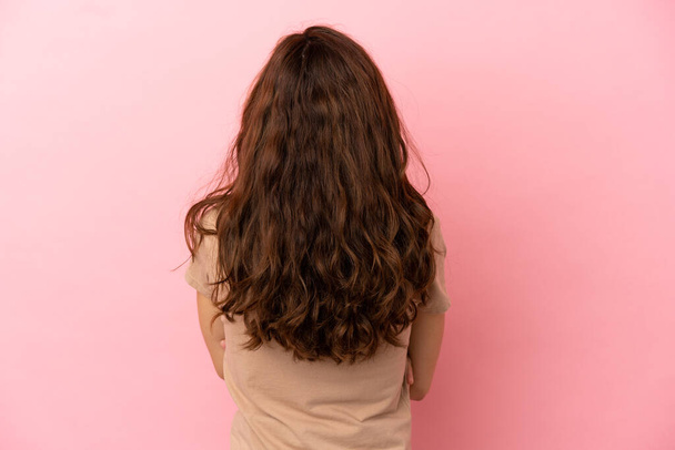 Молода біла жінка ізольована на рожевому тлі в положенні спини
 - Фото, зображення
