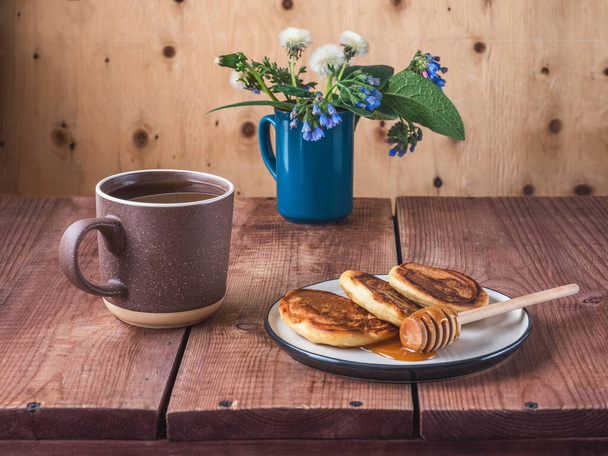 Pancakes with honey and spring bouquet in a blue mug, dandelions and blue Symphytum caucasicum - Photo, Image