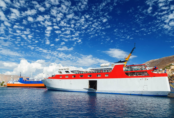 丘と青い空の背景にシミ島の湾でドデカニソスの定期的な海上交通の2ギリシャの旅客フェリー - 写真・画像