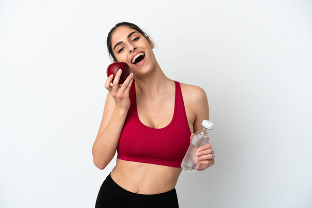 Молодая белая женщина изолирована на белом фоне с бутылкой воды и едят яблоко - Фото, изображение