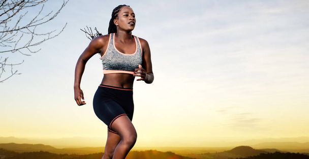 Крупный план действий портрет молодой африканской спортсменки бег трусцой. Мускулистая девушка в спортивной одежде на фоне заката с копией пространства.. - Фото, изображение