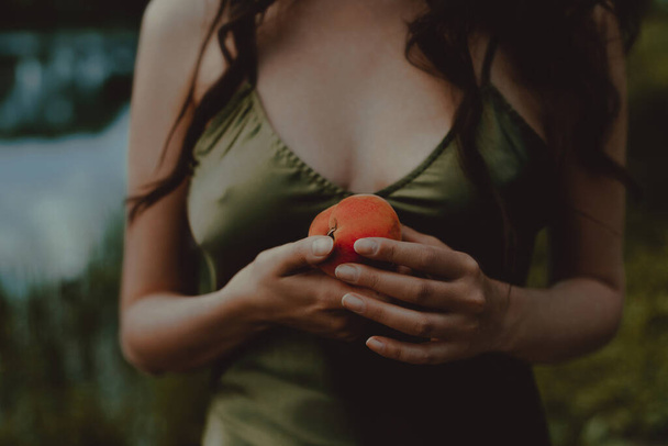Young woman is holding peach. Anonymous portrait. Lifestyle, outdoor recreation on weekends - Foto, imagen