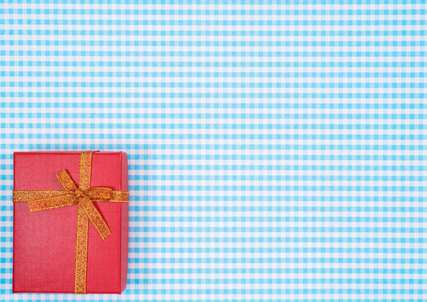 Geschenkkarton mit roter Isolierung auf kariertem Hintergrund. Festtagsdekoration für Muttertag oder Frauentag. - Foto, Bild