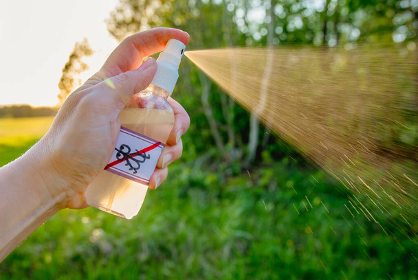 Vista de cerca de la mano de la mujer sosteniendo y utilizando aceite esencial casero a base de repelente de mosquitos al aire libre en el bosque. - Foto, Imagen