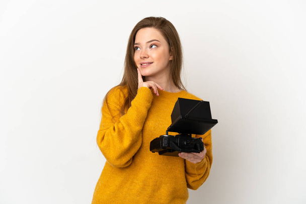 Teenager dívka drží drone dálkové ovládání nad izolovaným bílým pozadím myšlení nápad při pohledu nahoru - Fotografie, Obrázek