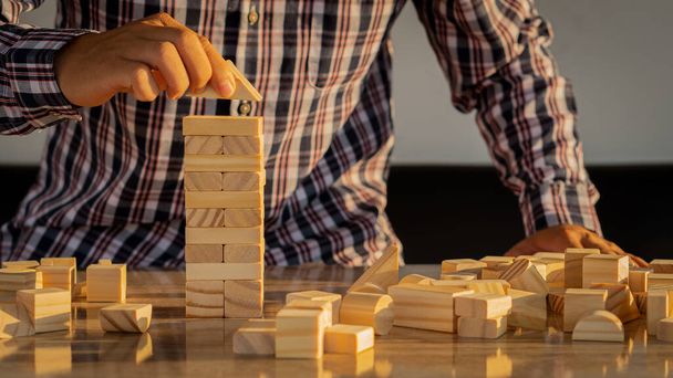 Business Risk Zakenman verdedigt het houten blok op tafel, planning en strategie in alternatieve bedrijfsrisico 's - Foto, afbeelding