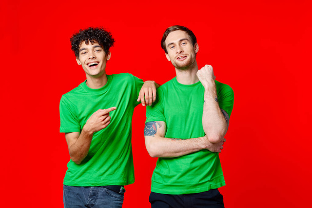 緑のTシャツを着た2人の陽気な友人が隣に立っています - 写真・画像