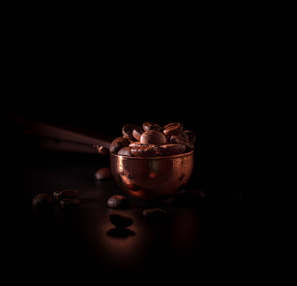 Ψητά φασόλια καφέ στο κουτάλι χαλκού σε σκούρο φόντο.  - Φωτογραφία, εικόνα