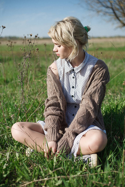 giovane attraente femmina caucasica seduta su un terreno al campo nella giornata di sole - Foto, immagini