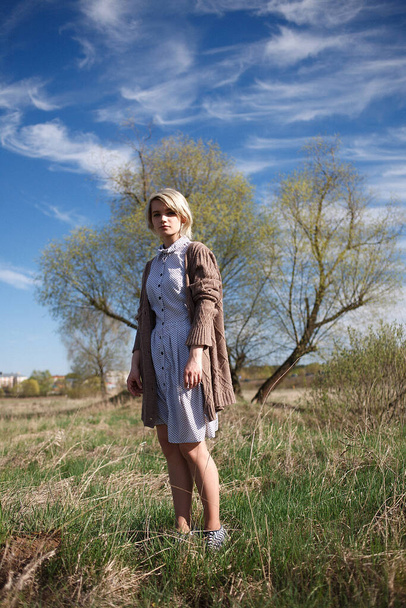 young attractive caucasian female stands at field on sunny day in front of tree - Photo, image