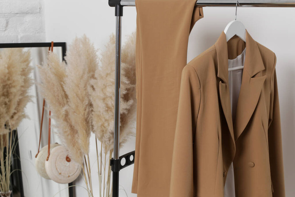 Women's Clothes. Clothes rack, beige blazer and trousers in fashion atelier. - Fotó, kép