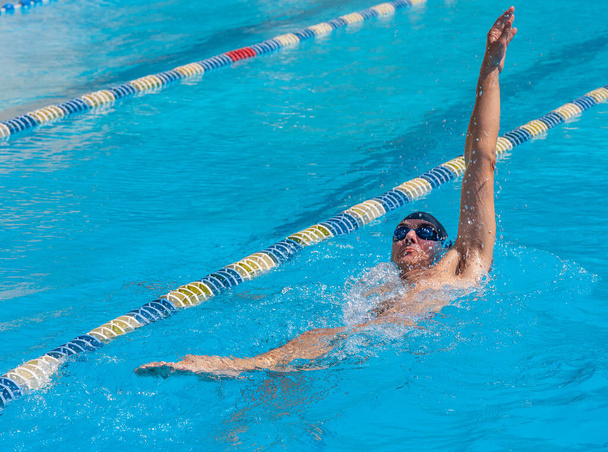 an adult, former swimmer, trains in a public swimming pool, with sun - Фото, изображение