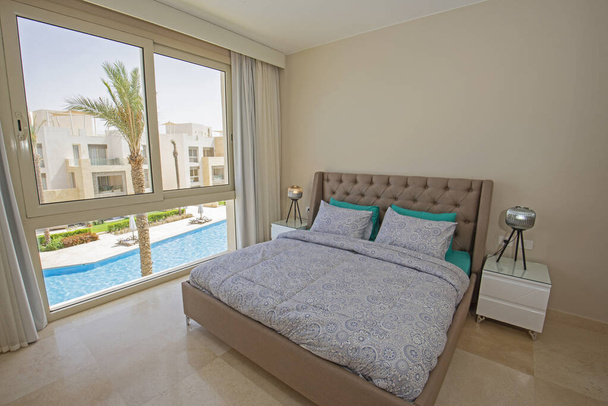 Decoración de diseño de interiores decoración de lujosos show home dormitorio mostrando muebles y cama doble en resort con vista a la piscina - Foto, Imagen