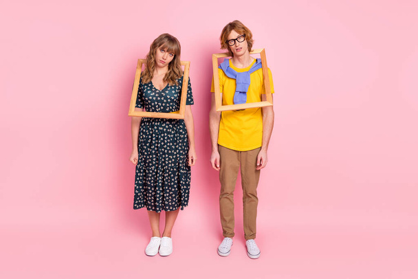 Full body photo of exhausted unhappy people couple wear dress yellow t-shirt pants wooden frame isolated on pink color background - Photo, Image