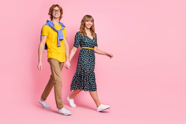 Full length body size view of nice cheerful couple holding hands walking isolated over pink pastel color background - Foto, Bild