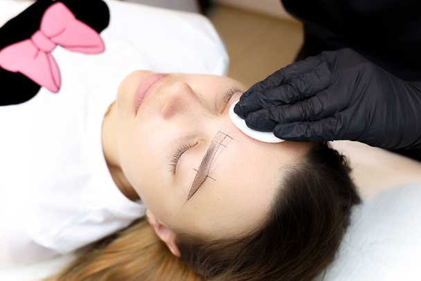 the permanent makeup artist treats the client's skin around the eyes after the tattoo procedure - Photo, Image