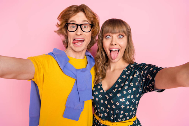 Photo of optimistic nice couple do selfie tongue out wear colorful clothes isolated on pastel pink background - Foto, Imagen