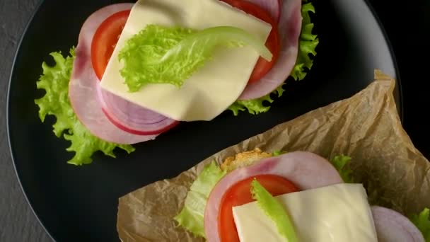 Delicious sandwiches rotate on a dark stone background, flatlay view. - Footage, Video