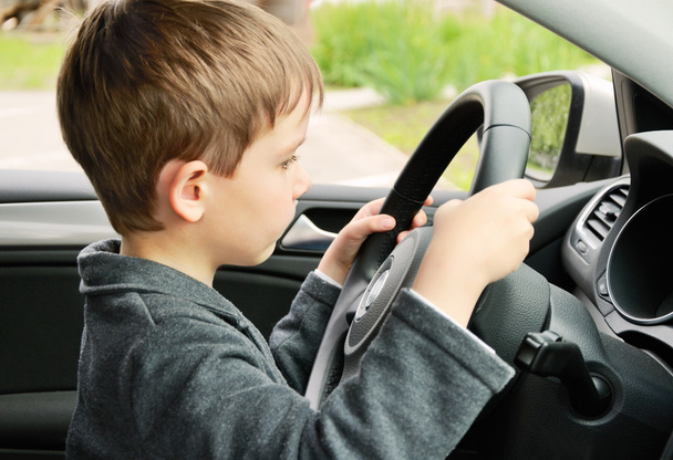 мальчик за рулем автомобиля и смотрит на дорогу
 - Фото, изображение