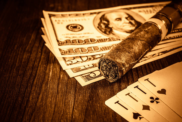 Cuban cigar with playing cards and money on the table mahogany.  - Photo, Image