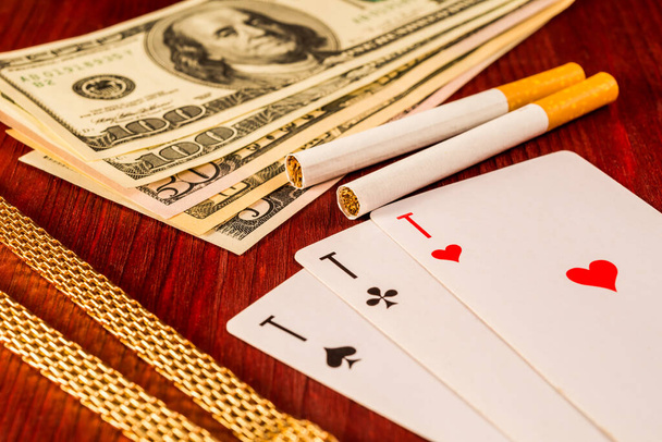 Cigarettes and golden chain with playing cards and money on the  - Photo, Image