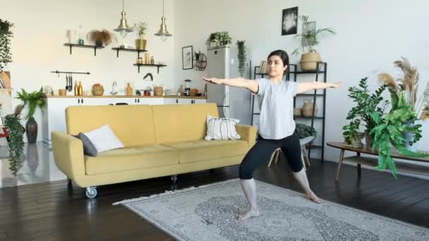 Lekcje jogi w domu. Młoda Hinduska kobieta ćwiczy jogę w domu. Elastyczna dziewczyna robi rozciąganie podczas pobytu na podłodze - Materiał filmowy, wideo