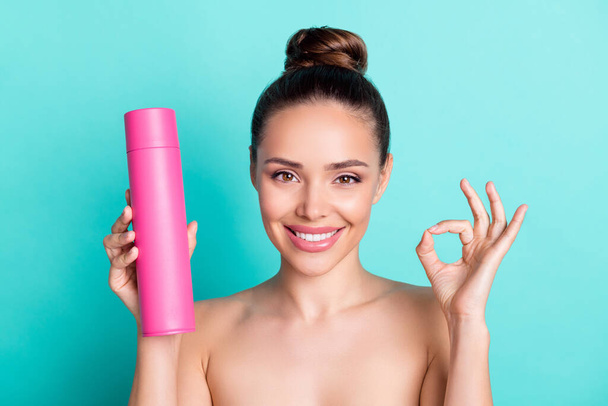 Portrait of attractive trendy naked cheerful girl holding spray showing ok-sign isolated over bright teal turquoise color background - Фото, зображення