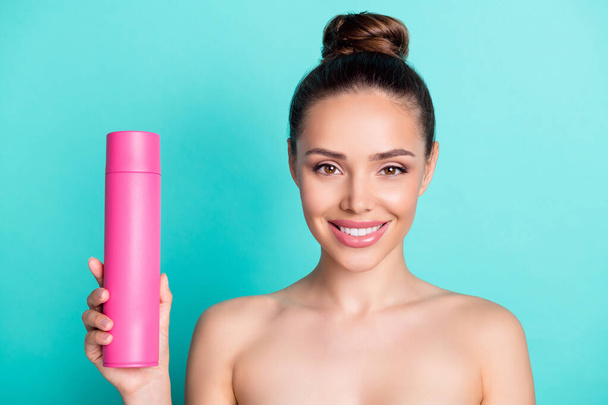 Portrait of attractive naked nude cheerful girl holding in hand pink bottle spray isolated over bright teal turquoise color background - Photo, image