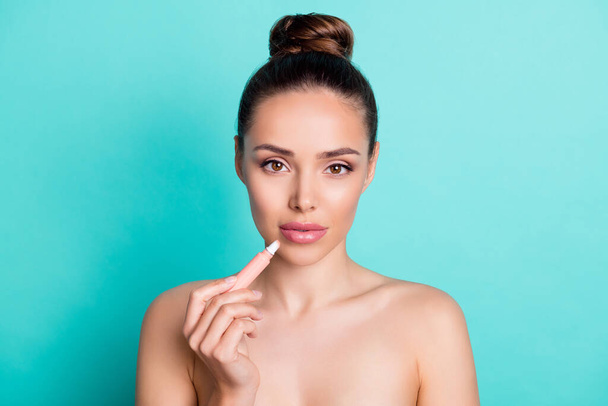 Portrait of attractive naked nude girl applying lip balm form correction scrub isolated over bright teal turquoise color background - Фото, зображення