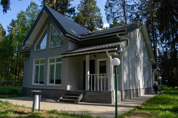 Внешний вид современного дома с верандой завершен серым сайдингом. - Фото, изображение