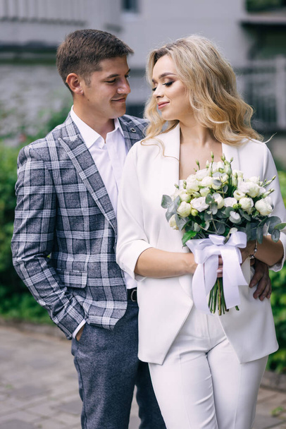 stunning bride holding a bouquet of roses and smiling groom. Happy couple. - Foto, afbeelding