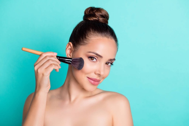 Portrait of attractive trendy girl using brush applying cc bb cream base isolated over bright teal turquoise color background - Φωτογραφία, εικόνα