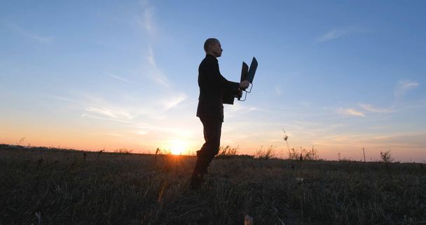 Silhouette eines jungen männlichen Kung-Fu-Kämpfers, der bei Sonnenuntergang allein auf den Feldern übt - Foto, Bild