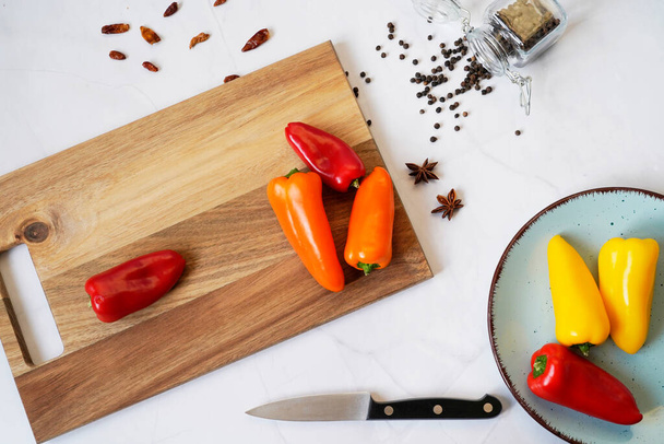 Background of food on a white marble table. Spices and knife on a wooden cutting board, top view, flat. - Foto, afbeelding