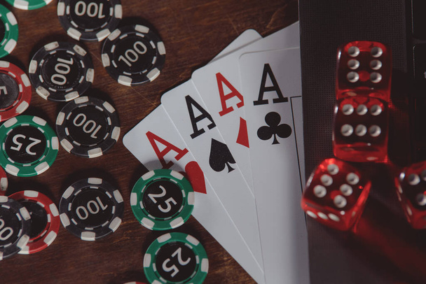 Spielchips, rote Würfel, Karten mit Assen und Laptop in Großaufnahme. Ansicht von oben. Poker-Konzept - Foto, Bild