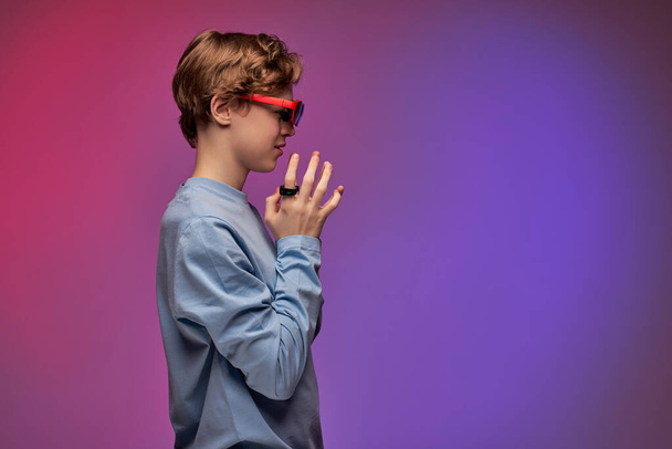 Teenage boy in virtual reality glasses enjoying 3D gadget technology, controllers on fingers - Foto, immagini