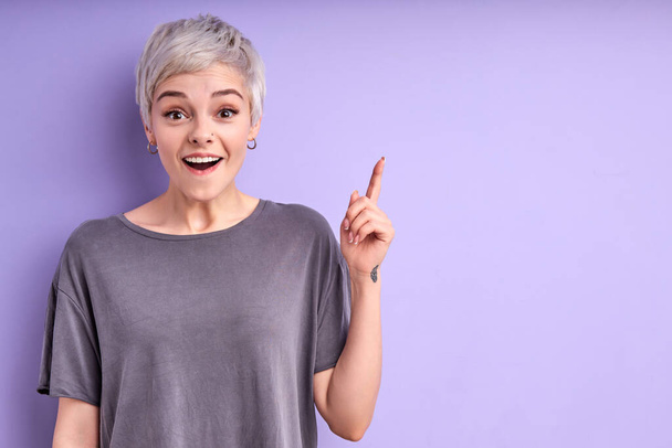Funny adult woman with short hair showing up on advertisement, keep finger up - Fotó, kép