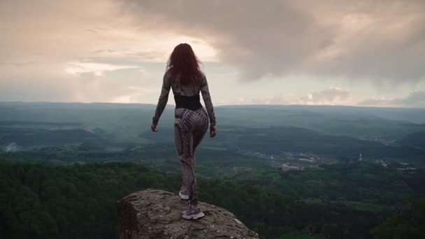 Hoikka tyttö seisoo Top Mountain ja nostaa kätensä puolin upea maisema - Materiaali, video