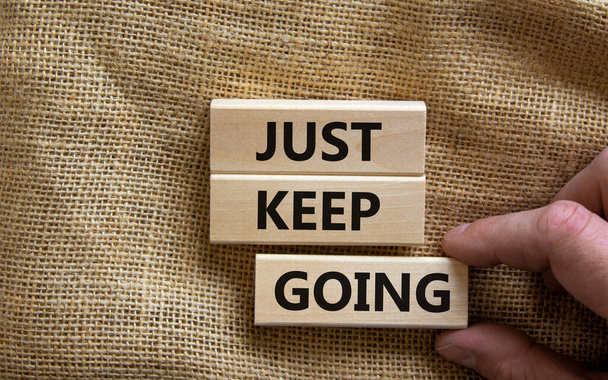 Just keep going symbol. Wooden blocks with words 'Just keep going'. Beautiful canvas background, businessman hand. Business, just keep going concept, copy space. - Fotó, kép