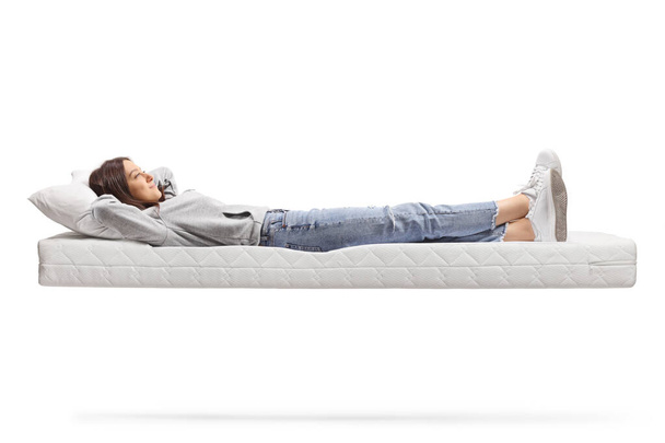 Full length shot of a young female in jeans resting on a floating mattress isolated on white background - Foto, immagini