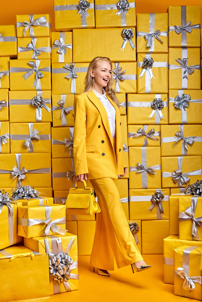 rejoicing woman shopping buy new handbag wearing stylish outfit in yellow party suit - Fotó, kép