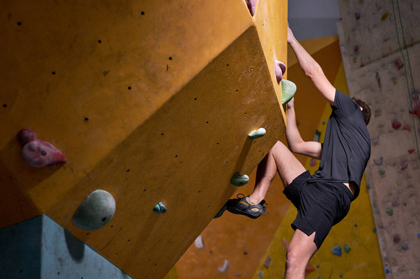 Uomo adulto in abbigliamento sportivo arrampicata parete rocciosa indoor. Concetto di vita sportiva. - Foto, immagini