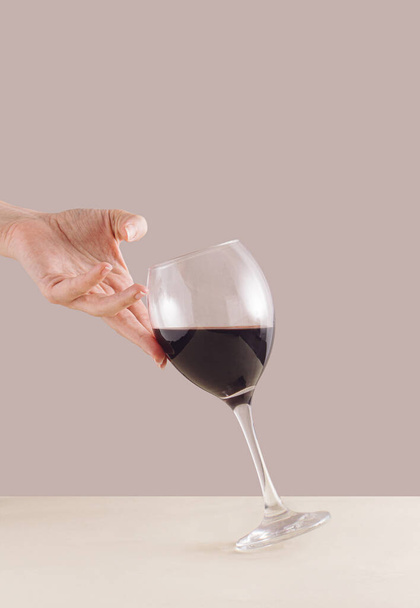 Woman hand holding on glass of red wine. Stylish minimal aesthetic. - Photo, Image