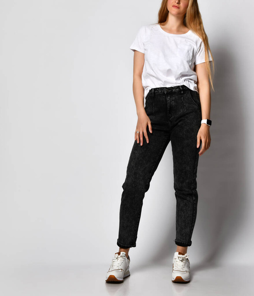 Studio shot of unrecognizable stylish young woman in black jeans and white t-shirt. - Foto, Imagen