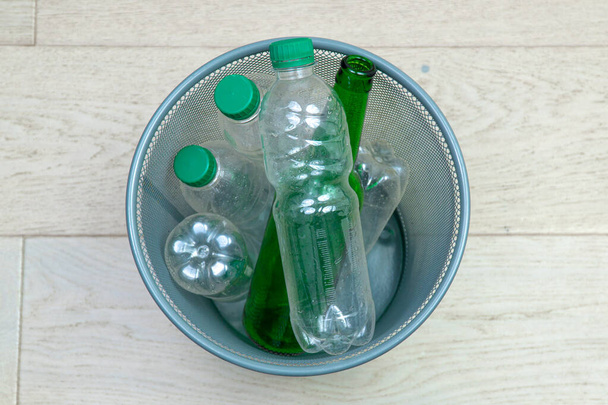Six different plastic and glass bottles in the office trash can. Ecology and recycling of waste from various raw materials - Foto, imagen