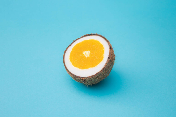 Pomeranč v kokosu na modrém pozadí. Minimální design. - Fotografie, Obrázek