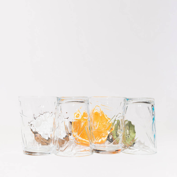 Скляні чашки на білому тлі і позаду них кокос, апельсин і ківі. Копіювати простір
. - Фото, зображення
