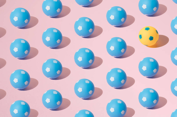 Arranged blue and yellow soccer ball on a pink background. Minimum pattern. - 写真・画像